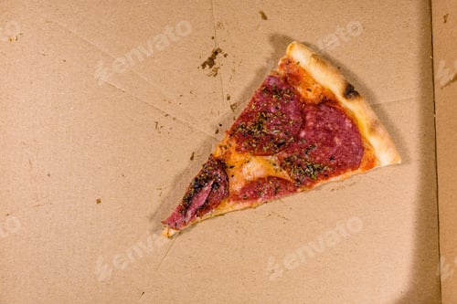Preview: Last Piece Of Pizza With Salami Sausage And Parmesan Cheese In Cardboard Box