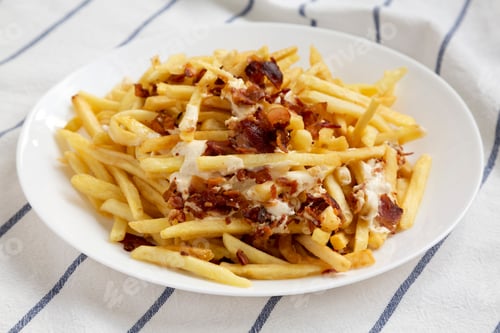 Preview: French Fries With Cheese Sauce And Bacon On A White Plate, Side View. Close-Up