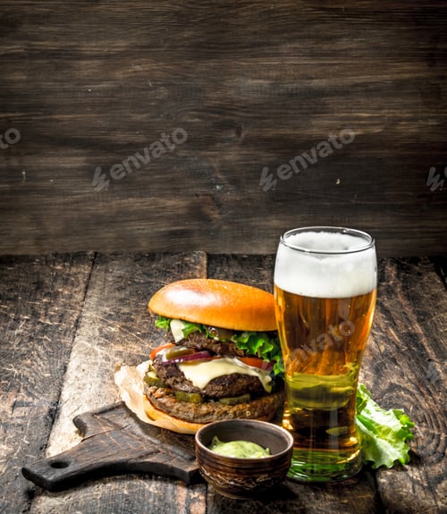 Preview: Fast Food. A Big Burger With Beef And A Glass Of Beer. On A Wooden Background.