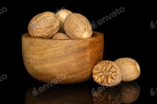 Preview: Group Of Five Whole One Half Of Dry Brown Nutmeg In Tiny Wooden Bowl Isolated On Black Glass