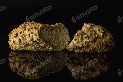 Preview: Group Of Two Halves Of Fresh Cereal Baguette One Sliced Isolated On Black Glass