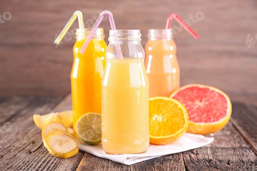 Juice Bottles with Citrus Fruits on Wooden Table