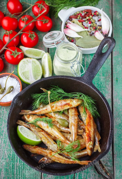 Preview: Fried Smelt In The Pan On The Table With A Sauce, Lime, Tomatoes, Dill And Garlic. Fried Small