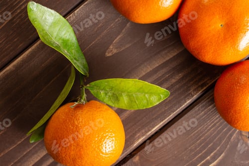 Preview: Group Of Four Whole Fresh Orange Mandarine With Green Leaves Flatlay On Brown Wood
