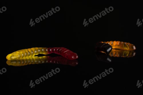 Preview: Group Of Three Whole Colourful Jelly Worm Candy Isolated On Black Glass