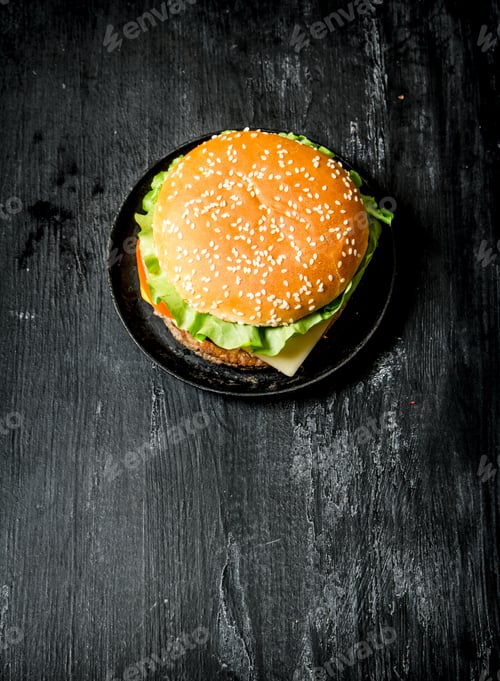 Preview: Hamburger With Cheese, Meat Cutlet And Vegetables. On A Black Chalkboard. Top View.