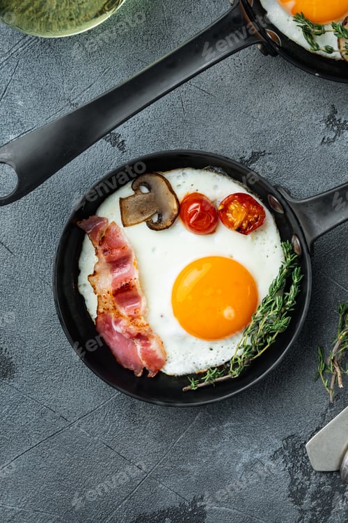 Preview: Fried Eggs With Bacon And Vegetables In Cast Iron Frying Pan, On Gray Background, Top View Flat Lay