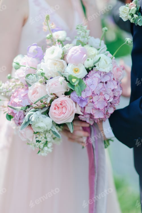 Preview: Closeup Bouquet Of Flowers With Bride Holding Groom Hands In Background. Concept Of Bridal Photo