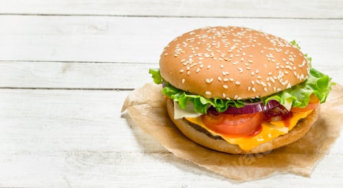 Preview: Burger With Beef, Cheese And Vegetables On Paper. On A White Wooden Background.