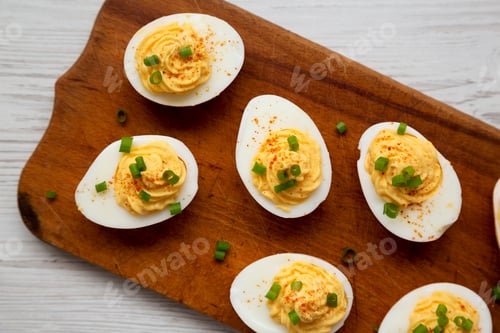 Preview: Homemade Deviled Eggs With Chives On A Rustic Wooden Board On A White Wooden Background, Top View