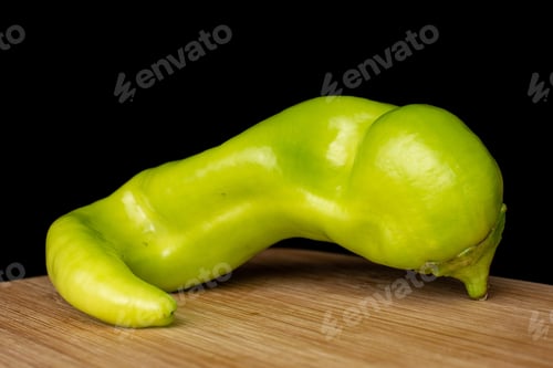 Preview: One Whole Hot Green Pepper Banana On Bamboo Cutting Board Isolated On Black Glass