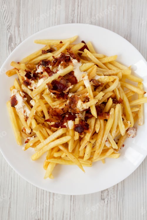 Preview: French Fries With Cheese Sauce And Bacon On A White Plate Over White Wooden Background, Top View