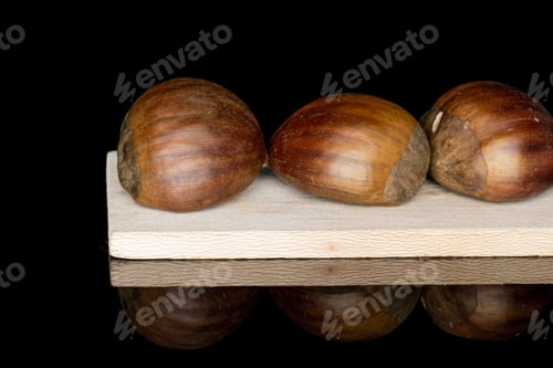 Preview: Group Of Three Whole Edible Brown Chestnut On Wooden Cutting Board Isolated On Black Glass