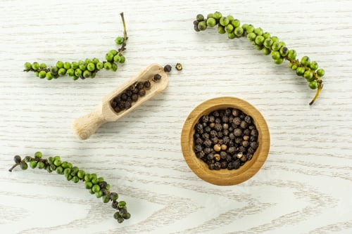 Preview: Unripe Drupes Of Fresh Black Pepper Flatlay On Grey Wood Backgound Four Bunches One Wooden Bowl And