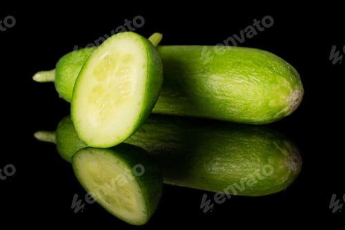 Preview: Group Of One Whole One Piece Of Mini Green Cucumber Isolated On Black Glass
