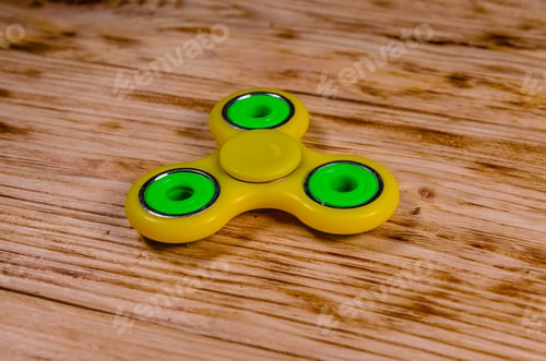 Preview: Yellow Fidget Spinner On Rustic Wooden Desk