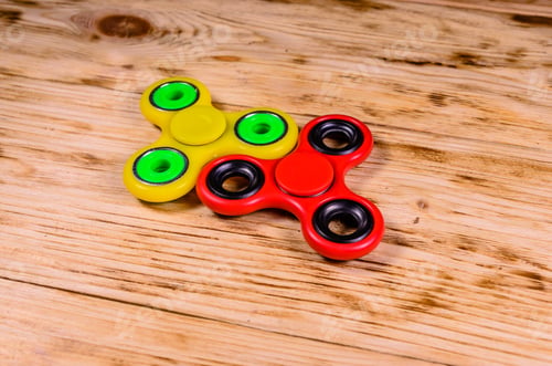 Preview: Yellow And Red Fidget Spinners On Rustic Wooden Desk