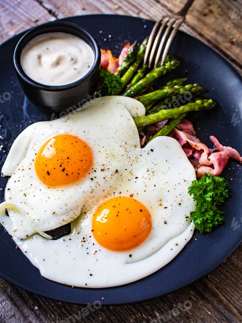 Preview: Tasty Breakfast. Sunny Side Up Eggs With Green Asparagus, Fried Bacon And Garlic Dip Served On