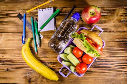 Preview: Bottle Of Water, Banana, Ripe Apple, Different Stationeries And Lunch Box With Hamburger, Cucumbers