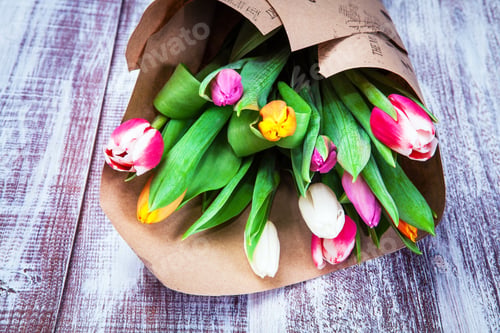 Preview: The Bouquet Of Tulips Is Wrapped In A Paper Isolated On A Wood Background