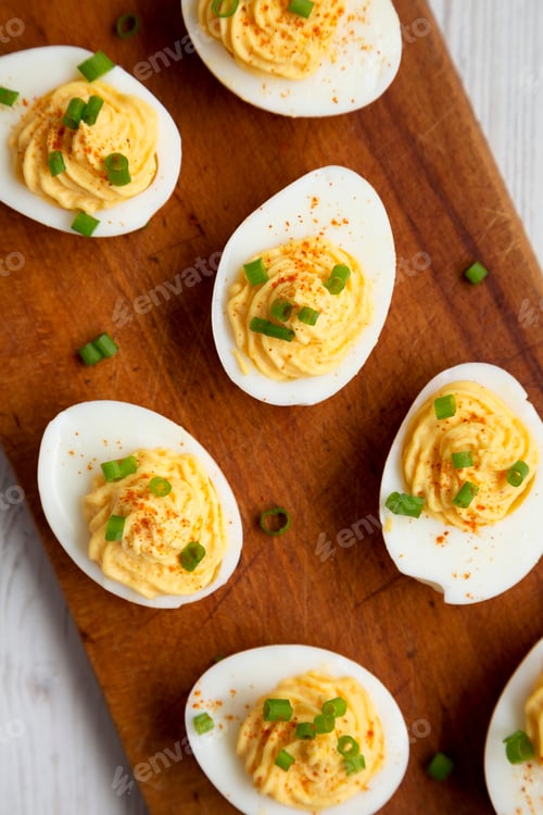 Preview: Homemade Deviled Eggs With Chives On A Rustic Wooden Board On A White Wooden Background, Top View