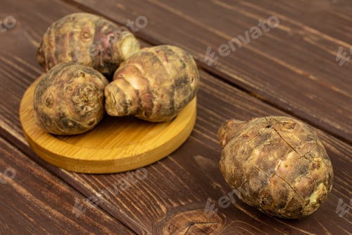 Preview: Group Of Four Whole Fresh Brown Jerusalem Artichoke On Bamboo Coaster On Brown Wood