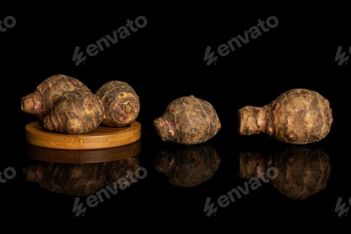 Preview: Group Of Five Whole Fresh Brown Jerusalem Artichoke On Bamboo Coaster Isolated On Black Glass