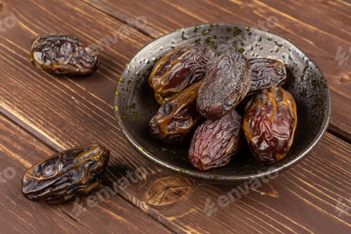 Preview: Lot Of Whole Dry Brown Date Fruit In Dark Ceramic Bowl On Brown Wood