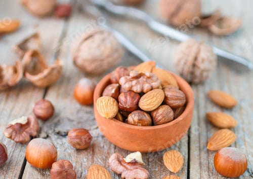 Preview: Mixed Nuts In A Bowl On A Wooden Background. Almond, Hazelnut And Walnut. Nuts In A Clay Bowl On
