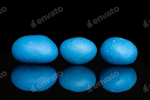 Preview: Group Of Three Whole Blue Sugared Nut Dragee Isolated On Black Glass