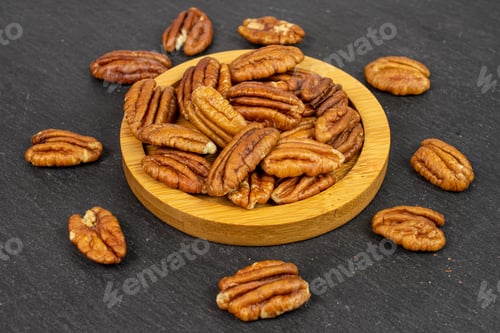 Preview: Lot Of Whole Dry Brown Pecan Nut On Bamboo Coaster On Grey Stone
