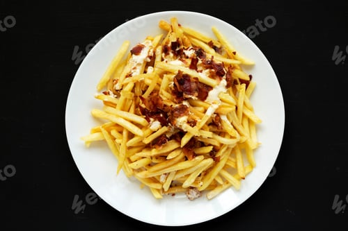Preview: Top View, French Fries With Cheese Sauce And Bacon On A White Plate Over Black Background. Flat