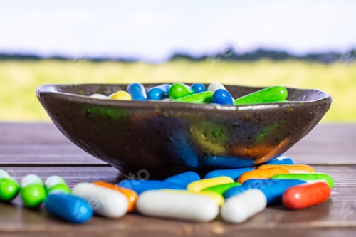 Preview: Lot Of Whole Sweet Licorice Comfit On Grey Ceramic Plate With Green Wheat Field In Background