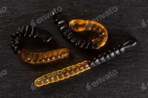 Preview: Group Of Three Whole Orange Brown Colourful Jelly Worm Candy Flatlay On Grey Stone