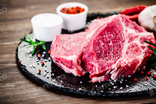 Preview: Raw Pork On Black Stone On Wooden Background