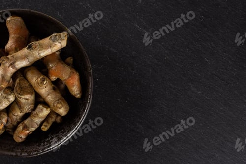 Preview: Lot Of Whole Bright Turmeric Rhizome Copyspace On Right On Grey Ceramic Plate Flatlay On Grey Stone