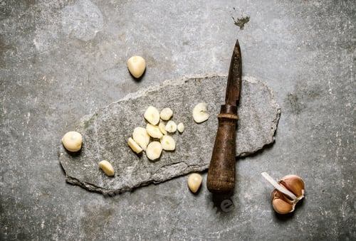 Preview: Chopped Garlic And Old Knife On A Stone Stand. On A Stone Background.