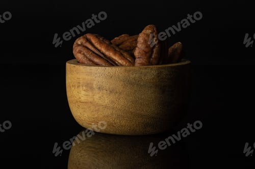 Preview: Lot Of Whole Fresh Brown Pecan Nut Half In A Wooden Bowl Isolated On Black Glass