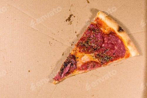 Preview: Last Piece Of Pizza With Salami Sausage And Parmesan Cheese In Cardboard Box