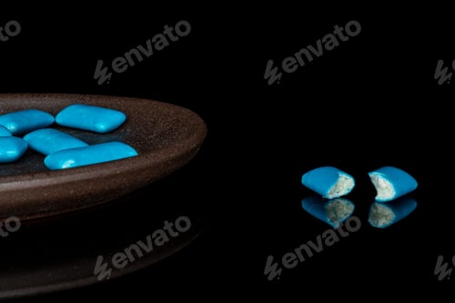 Preview: Group Of Six Whole Two Halves Of Blue Chewing Gum With Brown Ceramic Coaster Isolated On Black Glass