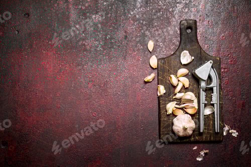 Preview: Fragrant Garlic With A Press Tool On A Wooden Board. On Rustic Background.