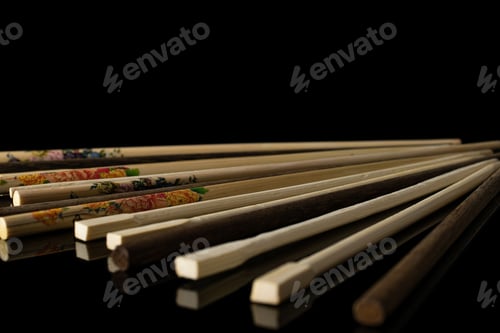Preview: Lot Of Whole Asian Brown Chopsticks In Line Isolated On Black Glass