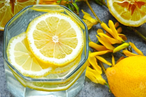 Preview: Detox Water With Lemon Juice. Lemon Water. Yellow Flowers On The Branches. Water With Lemon Wedges