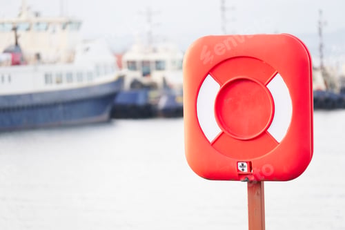 Preview: Red Ring For Water Safety At Sea Dock And Ships In Background
