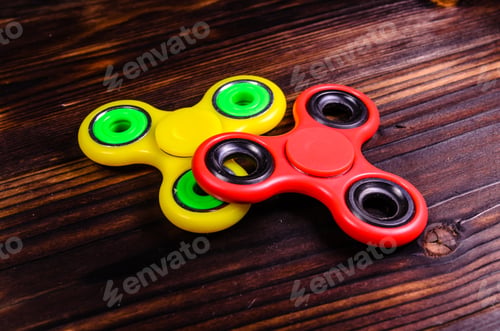 Preview: Yellow And Red Fidget Spinners On Rustic Wooden Desk