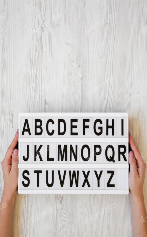 Preview: Top View, Female Hands Hold Modern Board With English Alphabet Over White Wooden Background, From