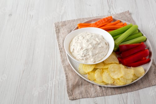 Preview: Homemade Caramelized Onion Dip With Potato Chips, Celery, Pepper And Carrot On A White Wooden