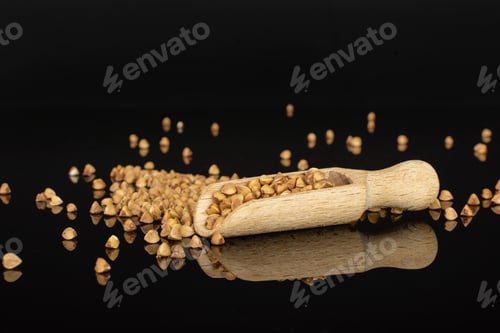Preview: Lot Of Whole Hulled Raw Brown Buckwheat Grain With Wooden Scoop Isolated On Black Glass