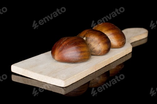 Preview: Group Of Three Whole Edible Brown Chestnut On Wooden Cutting Board Isolated On Black Glass