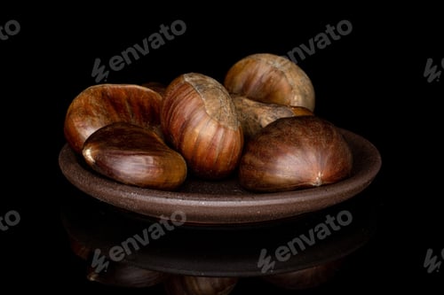 Preview: Group Of Six Whole Edible Brown Chestnut With Brown Ceramic Coaster Isolated On Black Glass